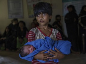 In this Sept. 13, 2017, file photo, Rohingya Muslim girl Afeefa Bebi, who crossed over from Myanmar into Bangladesh on Sept. 3, 2017 holds her  brother