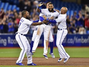 Toronto Blue Jays shortstop Richard Urena is mobbed by teammates, from left, Teoscar Hernandez, Kevin Pillar and Ryan Goins after hitting a game winning RBI single against the Baltimore Orioles during the ninth of their game in Toronto on Tuesday night.
