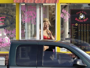 In a 2010 file photo, a barista at a Grab-N-Go Bikini Hut espresso stand holds money as she waves to a customer, just outside the city limits of Everett, Wash., in Snohomish County. Seven bikini baristas and the owner of a chain of the coffee stands called "Hillbilly Hotties" sued the city of Everett, Washington, on Monday, Sept. 11, 2017, saying two recently passed ordinances banning bare skin violate their right to free expression.