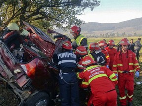 In this picture provided by Romanian General Inspectorate for Emergency Situations,  emergency services work at the scene of an accident, in Saratel, northern Romania, Thursday, Sept. 14, 2017.  A Romanian official says a car carrying a group of British volunteers has slammed into a tree, killing one and injuring three others. Spokesman for the Bistrita emergency services Marius Rus told The Associated Press the driver lost control of the vehicle early Thursday in the northern village of Saratel and veered off the road. (Inspectoratul Pentru Situatii de Urgenta via AP)