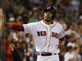 Boston Red Sox's Mookie Betts high fives a fan through the protective netting after scoring the tying run during the ninth inning of a baseball game against the Toronto Blue Jays at Fenway Park in Boston Tuesday, Sept. 5, 2017. (AP Photo/Winslow Townson)