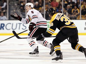 Chicago Blackhawks defenseman Connor Murphy reaches for a loose puck behind Boston Bruins' Matt Beleskey during the first period of an NHL preseason hockey game in Boston, Monday, Sept. 25, 2017. (AP Photo/Winslow Townson)