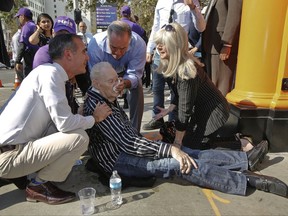 Los Angeles Mayor Eric Garcetti, left, comes to the aid of an unidentified man who collapsed in downtown Los Angeles Thursday, Aug. 31, 2017. The temperature in downtown Los Angeles shot past 90 degrees early in the day and a spectator collapsed just as Mayor Eric Garcetti was about to start a late-morning ceremony to mark the reopening of the city's historic Angels Flight funicular railroad. The man appeared to recover but was taken away by paramedics. (AP Photo/Damian Dovarganes)