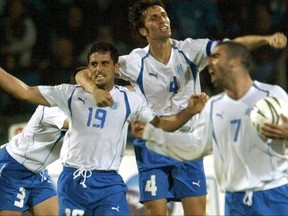 FILE - In this Match 26, 2005 file photo, Israel's Abas Suan , left, and Arik Benado , center, celebrate after Suan scored during the World Cup qualifying soccer match against Ireland in Ramat Gan stadium in Tel Aviv, Israel. President Trump's clash with professional football players who knelt during the Star Spangled Banner last weekend in September, 2017 has set off a heated debate over etiquette during the national anthem, but the U.S. is not alone. (AP Photo/Ariel Schalit, File)