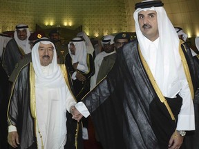 FILE- In this June 7, 2017 file photo, released by Kuwait News Agency, KUNA, Kuwait's Emir Sheikh Sabah Al Ahmad Al Sabah, left, holds the hand of Qatar's Emir Sheikh Tamim bin Hamad Al Thani in Doha, Qatar. Qatar likely faces a deadline this weekend to comply with a list of demands issued to it by Arab nations that have cut diplomatic ties to the energy-rich country, though its leaders already have dismissed the ultimatum. (KUNA via AP, File)