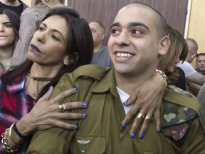 FILE - In this Feb. 21, 2017 file photo, Israeli soldier Elor Azaria is embraced by his mother at the start of his sentencing hearing in Tel Aviv, Israel. Israel's chief of staff, Lt. Gen. Gadi Eisenkot, said in a letter published Wednesday, Sept. 27, 2017 that he was reducing the 18-month prison sentence of Azaria, a soldier convicted of fatally shooting an incapacitated Palestinian attacker last year. Eisenkot cut four months off Azaria's jail term, which began last month, citing "benevolence and mercy considerations." (Jim Hollander, Pool, via AP, File)