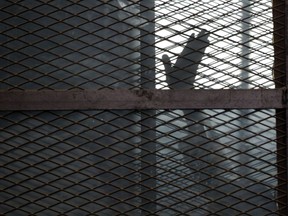 FILE - In this Aug. 22, 2015 file photo, a Muslim Brotherhood member gestures from a defendants cage in a courtroom in Torah prison, southern Cairo, Egypt. Human Rights Watch, an international rights group, is alleging systematic torture inside Egyptian police stations and Interior Ministry headquarters where officers act in "almost total impunity." In a 63-page study released Wednesday, Aug. 6, 2017,  HRW said President Abdel-Fattah el-Sissi's pursuit of stability comes "at any cost." (AP Photo/Amr Nabil, File)