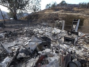 The charred remains of a burned out home are seen Monday, Sept. 4, 2017, in the Sunland-Tujunga section of Los Angeles. Wildfires forced thousands to flee their homes across the U.S. West during a sweltering, smoke-shrouded holiday weekend of record heat. (AP Photo/Ringo H.W. Chiu)