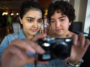 Cancer patients Yasmine Dabir, 17, left, and Salome Oliveira dos Santos take a picture with one of the cameras supplied by the hospital for the photo voice project, on display at the Sick Kids Hospital in Toronto on Monday, Sept. 25, 2017. THE CANADIAN PRESS/Chris Donovan