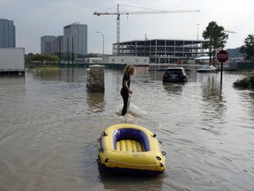 In this Sunday, Sept. 3, 2017 photo, Christian Carr, 17, of Austin, Texas, tows his raft to help residents bring groceries to their flooded Heights Park Row apartment complex in Houston. Equipped with an inflatable yellow raft and fortified with duct tape that might come in handy, Carr and his mother Kelli Shofstall set out on a 165-mile drive from Austin that led them to neighborhood upon neighborhood of dry Houston streets and little sign their help was needed. It would take more than a day of driving around following outdated flood maps before they found a street under water where they could ferry tenants to and from a marooned apartment complex. (AP Photo/Brian Melley)
