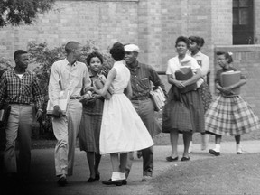 FILE - In this Oct. 2, 1957, file photo, the first black students to enroll at Central High School in Little Rock, Ark., leave the building and walk toward a waiting Army station wagon following their classes. Monday, Sept. 25, 2017, marks the 60th anniversary of when nine black students enrolled at the Arkansas school. One of the nine students is obscured by another student in this photograph. (AP Photo/Ferd Kaufman, File)