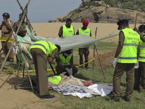 Sri Lankan police officers examine the body of British journalist Paul Stewart McClean, after it was recovered from a lagoon near Panama, Sri Lanka, Friday.