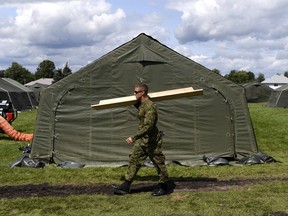 A Canadian Forces member helps set up the interim lodging site, outside Cornwall's Nav Centre, which is temporarily housing U.S. asylum seekers, on Wednesday, Aug. 23, 2017