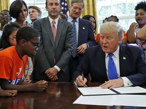 President Donald Trump signs a memorandum to expand access to STEM, science technology engineering and math, education in the Oval Office of the White House, Monday, Sept. 25, 2017, in Washington. (AP Photo/Alex Brandon)