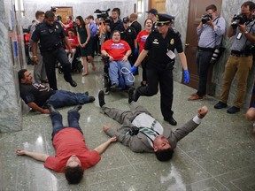 U.S. Capitol Police begin to detain protesters laying on the ground in an attempt to maintain order in the hallways outside the Senate Finance Committee hearing on the last-ditch GOP push to overhaul the nation's health care system, on Capitol Hill in Washington, Monday, Sept. 25, 2017. (AP Photo/Susan Walsh)