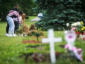 In this Aug. 8, 2017 photo, Tyzell Cephas, 23, accompanied by his wife, Takira Jones-Cephas, and cousin, Laqueen McDuffie, visits the grave of his 16-year-old sister, Tynesia, at Silverbrook Cemetery in Wilmington, Del. Tynesia was gunned down while trying to break up a fight on Wilmington's East Side. Her boyfriend and his family watched as she took her last breaths on a row home floor after being shot on Kirkwood Street. (Suchat Pederson/The Wilmington News-Journal via AP)