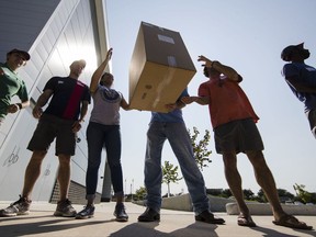 FILE - In Wednesday, Sept. 6, 2017, file photo, volunteers move boxes of shoes donated by Mythiquer Pickett for students affected by Hurricane Harvey on at the Delmar Field House in Houston. More than 50 local and national charities have raised more than $350 million in the nearly three weeks since Hurricane Harvey struck the Texas Gulf Coast. The disparate groups are now trying to decide on priorities while some storm victims wait for help. (AP Photo/Matt Rourke, File)
