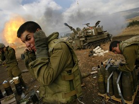 FILE - In this July 21, 2006 file photo, Israeli soldiers cover their ears as an artillery unit fires shells towards southern Lebanon from a position near Kiryat Shmona in northern Israel, near the border with Lebanon. With President Bashar Assad seemingly poised to survive the Syrian civil war, Israeli leaders are growing nervous about the intentions of his Iranian patrons and their emerging corridor of influence across the region. (AP Photo/David Guttenfelder, File)