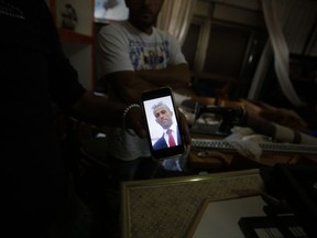 FILE - In this Tuesday, Sept. 26, 2017 file photo, a relative shows a photo of Nimr Jamal who opened fire at the entrance of a settlement Tuesday killing three people, at his family's home in the West Bank village of Beit Surik. An Israeli Shin Bet security service investigation revealed that the 37-year-old Jamal was a troubled man with a history of domestic violence, whose wife had recently fled to Jordan to escape his abuse, leaving him behind with their four children. According to this account, Jamal snapped, but instead of killing himself or his relatives in anonymity he decided to go out in a blaze of glory amid the maelstrom that is the Israeli-Palestinian conflict. (AP Photo/Nasser Shiyoukhi, File)