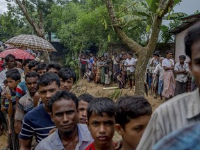 Newly arrived Rohingya wait for their turn to collect building material for their shelters distributed by aid agencies in Kutupalong refugee camp, Bangladesh, Wednesday, Sept. 13, 2017. With Rohingya refugees still flooding across the border from Myanmar, those packed into camps and makeshift settlements in Bangladesh were becoming desperate for scant basic resources as hunger and illness soared. (AP Photo/Dar Yasin)