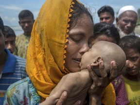 A Rohingya Muslim woman Hanida Begum, who crossed over from Myanmar into Bangladesh, kisses her infant son Abdul Masood who died when the boat they were traveling in capsized just before reaching the shore of the Bay of Bengal, in Shah Porir Dwip, Bangladesh, Thursday, Sept. 14, 2017. Nearly three weeks into a mass exodus of Rohingya fleeing violence in Myanmar, thousands were still flooding across the border Thursday in search of help and safety in teeming refugee settlements in Bangladesh. (AP Photo/Dar Yasin)