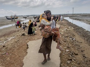 A Rohingya Muslim man Abdul Kareem walks towards a refugee camp carrying his mother Alima Khatoon after crossing over from Myanmar into Bangladesh, at Teknaf, Bangladesh, Saturday, Sept. 16, 2017. United Nations agencies say an estimated 409,000 Rohingya Muslims have fled to Bangladesh since Aug. 25, when deadly attacks by a Rohingya insurgent group on police posts prompted Myanmar's military to launch "clearance operations" in Rakhine state. Those fleeing have described indiscriminate attacks by security forces and Buddhist mobs. (AP Photo/Dar Yasin)