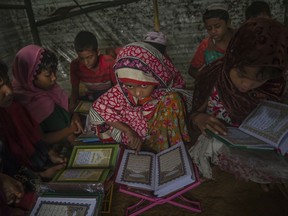 Rohingya Muslim girls, who crossed over from Myanmar into Bangladesh, attend recitation classes of the holy Quran in a newly opened madrasa, or religious school, at Kutupalong refugee camp, Bangladesh, Sunday, Sept. 24, 2017. The massive exodus of Rohingya Muslims fleeing Myanmar to escape brutal persecution appears to have slowed down, but several recent refugees say at least tens of thousands more are huddled near beaches or in forests waiting to escape. (AP Photo/Dar Yasin)
