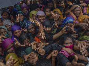 Rohingya Muslim women, who crossed over from Myanmar into Bangladesh, stretch their arms out to collect sanitary products distributed by aid agencies near Balukhali refugee camp, Bangladesh, Sunday, Sept. 17, 2017. Bangladeshi authorities on Sunday took steps to restrict the movement of Muslim Rohingya refugees living in crowded border camps after fleeing violence in Myanmar, while that nation's military chief maintained the chaos was the work of extremists seeking a stronghold in the country. (AP Photo/Dar Yasin)