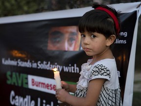 A Kashmiri girl holds a candle during a protest against the persecution of Myanmar's Rohingya Muslim minority, in Srinagar, Indian controlled Kashmir, Thursday, Sept. 7, 2017. Aid agencies were struggling to cope with a nonstop flood of Rohingya refugees into Bangladesh, where some 146,000 have arrived hungry and terrified after fleeing renewed violence in Myanmar. (AP Photo/Dar Yasin)