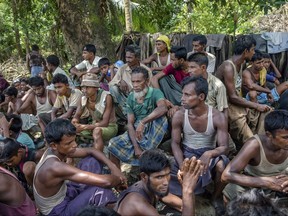 Rohingya Muslims, who recently crossed over from Myanmar, wait to carry food items across from Bangladesh's border towards no man's land where they have set up refugee camps in Tombru, Bangladesh, Friday, Sept. 15, 2017. Thousands of Rohingya are continuing to stream across the border, with U.N. officials and others demanding that Myanmar halt what they describe as a campaign of ethnic cleansing that has driven nearly 400,000 Rohingya to flee in the past three weeks. (AP Photo/Dar Yasin)