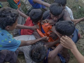 Rohingya Muslims, who crossed over from Myanmar into Bangladesh, fight for tarpaulin received in aid during its distribution near Balukhali refugee camp, Bangladesh, Monday, Sept. 25, 2017. More than 400,000 Rohingya Muslims have fled to Bangladesh since Aug. 25, when deadly attacks by a Rohingya insurgent group on police posts prompted Myanmar's military to launch "clearance operations" in Rakhine state. (AP Photo/Dar Yasin)