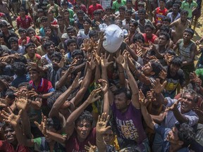 Rohingya Muslims, who crossed over from Myanmar into Bangladesh, stretch their arms out to catch a bag of rice thrown at them during distribution of aid near Balukhali refugee camp, Thursday, Sept. 21, 2017. With Rohingya refugees still flooding across the border from Myanmar, those packed into camps and makeshift settlements in Bangladesh are desperate for scant basic resources and fights erupt over food and water. (AP Photo/Dar Yasin)