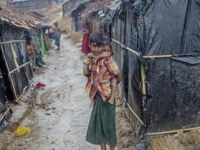 A Rohingya Muslim boy, who crossed over from Myanmar into Bangladesh, holds his brother outside his shelter as it rains in Balukhali refugee camp, Bangladesh, Thursday, Sept. 28, 2017. More than 400,000 Rohingya Muslims have fled to Bangladesh since Aug. 25, when deadly attacks by a Rohingya insurgent group on police posts prompted Myanmar's military to launch "clearance operations" in Rakhine state. (AP Photo/Dar Yasin)