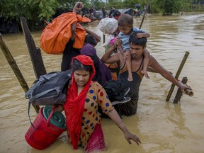 Rohingya Muslims, who crossed over from Myanmar into Bangladesh, use a makeshift footbridge as they move with their belongings after their camp was inundated with rainwater near Balukhali refugee camp, Bangladesh, Tuesday, Sept. 19, 2017. With a mass exodus of Rohingya Muslims sparking accusations of ethnic cleansing from the United Nations and others, Myanmar leader Aung San Suu Kyi on Tuesday said her country does not fear international scrutiny and invited diplomats to see some areas for themselves. (AP Photo/Dar Yasin)