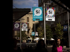 Banners calling to vote Yes in the independence referendum hang on poles as people walk along a street in Sabadell, near Barcelona, Spain, Thursday, Sept. 7, 2017. Spanish Prime Minister Mariano Rajoy's office says members of his cabinet are meeting Thursday to react to plans by Catalan leaders who have scheduled a vote on the region's secession from Spain. (AP Photo/Emilio Morenatti)