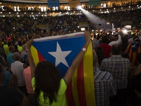 A woman holds an Estelada or Independence flag ahead of an event promoting the start of the campaigning for the ballot in Tarragona, about 100 kilometres south of Barcelona, Spain, Thursday, Sept. 14, 2017. Tension is mounting between Catalan and Spain's national leaders as Catalonia's president is set to open the "yes" campaign for a planned referendum on seceding from Spain Thursday. (AP Photo/Emilio Morenatti)