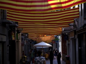 People walk along a street decorated with Catalan flags in Sabadell, near Barcelona, Spain, Thursday, Sept. 7, 2017. Spanish Prime Minister Mariano Rajoy's office says members of his cabinet are meeting Thursday to react to plans by Catalan leaders who have scheduled a vote on the region's secession from Spain. (AP Photo/Emilio Morenatti)