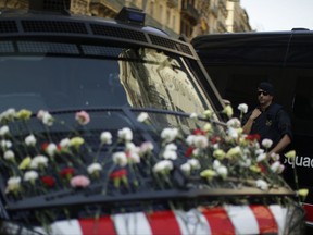 In this Sunday, Sept. 24, 2017 photo, a police officer of Catalan Mossos d'Esquadra stands next to his vehicle with flowers placed by people in Barcelona, Spain. (AP Photo/Manu Fernandez)