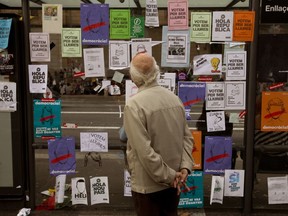 A man looks at banners encouraging people to vote for the referendum Barcelona, Spain Monday, Sept. 25, 2017. Grassroots groups driving Catalonia's independence movement say they have started distributing one million ballots to be used in a referendum on secession that the Spanish government has vowed to stop. (AP Photo/Emilio Morenatti)