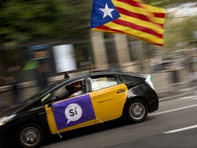 A man drives his taxi decorated with an estela flag and publicity supporting the Oct. 1 vote in Barcelona, Spain Friday, Sept. 22, 2017. Spain will deploy police reinforcements to Catalonia to help maintain order if an independence referendum pledged by Catalan officials but opposed by the national government goes ahead, officials said Friday. (AP Photo/Emilio Morenatti)