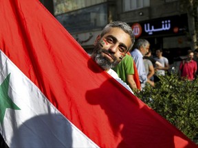 A Syrian soccer fan holds a Syrian flag ahead of a crucial match against Iran during the 2018 FIFA World Cup Russia Qualifier, in Tehran, Iran, Tuesday, Sept. 5, 2017. Millions of Syrians may finally have something to be joyful about in the midst of a long-running and ruinous war. Syria's national soccer team has a chance to qualify for next year's World Cup with a win today. (AP Photo/Ebrahim Noroozi)
