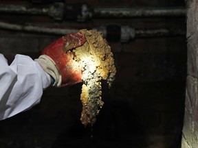 Thames Water field operation manager Natalie Stearn holds a piece of the Fatberg in an 1852-built sewer at Westminster in London, Monday, Sept. 25, 2017. British engineers are studying ways to dispose of yet another oversize "fatberg" threatening London's sewers. Stuart White of Thames Water says the latest fat blob is located in a busy area beneath Chinatown near London's famed Leicester Square. (AP Photo/Frank Augstein)
