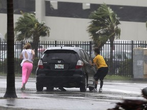 Stranded motorists try to get back in their car after a breakdown as Hurricane Irma bears down on the Florida Keys, Sunday, Sept. 10, 2017, in Hialeah, Fla. Wind gusts of 82 mph were reported in Miami. (AP Photo/Alan Diaz)
