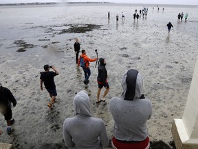People walk out on to what is normally four feet of water in Old Tampa Bay, Sunday, Sept. 10, 2017, in Tampa, Fla. Hurricane Irma, and an unusual low tide pushed water out almost hundreds of yards. (AP Photo/Chris O'Meara)