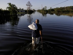 Jean Chatelier walks through a flooded street from Hurricane Irma after retrieving his uniform from his house to return to work today at a supermarket in Fort Myers, Fla., Tuesday, Sept. 12, 2017. Chatelier walked about a mile each way in knee-high water as a Publix supermarket was planning on reopening to the public today. "I want to go back to work. I want to help," said Chatelier. (AP Photo/David Goldman)