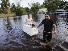 Alfonso Jose pulls his son Alfonso Jr., 2, in a cooler with his wife Cristina Ventura as they wade through their flooded street to reach an open convenience store in the wake of Hurricane Irma in Bonita Springs, Fla., Tuesday, Sept. 12, 2017. (AP Photo/David Goldman)