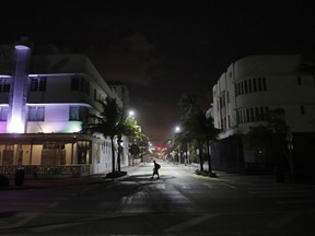 A lone pedestrian walks through the usual bustling South Beach ahead of Hurricane Irma in Miami Beach, Fla., Friday, Sept. 8, 2017. Florida has asked 5.6 million people to evacuate ahead of Hurricane Irma, or more than one quarter of the state's population, according to state emergency officials. (AP Photo/David Goldman)