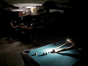 Lisa Borruso plays pool using a headlamp as the power remains out following Hurricane Irma at Gators' Crossroads in Naples, Fla., Monday, Sept. 11, 2017. Statewide, an estimated 13 million people, or two-thirds of Florida's population, remained without power. That's more than the population of New York and Los Angeles combined. Officials warned it could take weeks for electricity to be restored to everyone. (AP Photo/David Goldman)