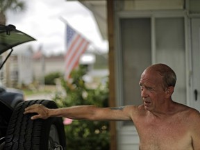Jeff Williams takes a break from securing his carport roof ahead of Hurricane Irma in the mobile home retirement community where he lives in Beverly Beach, Fla., Friday, Sept. 8, 2017. Florida is a haven for retirees, and residents of one coastal retirement community are leaving for Irma without knowing what to expect after the story. "What I'm worried about is the river meeting the ocean," Williams, said Friday as he added screws and metal supports to the carport of his trailer. "It that happens, it will take all of these places out." (AP Photo/David Goldman)