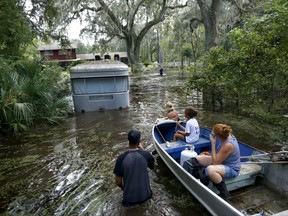 Family members ride in a small boat as Tony Holt's trailer to be pulled out of the flood waters from Hurricane Irma in Gainesville, Fla., Thursday Sept. 14, 2017, after Hurricane Irma. (Brad McClenny/The Gainesville Sun via AP)